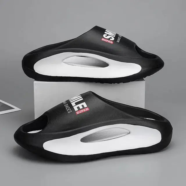 A pair of stylish black slip-on sandals with purple cushioned insoles, featuring cutout designs on the sides and toes, displayed on a white surface next to stacked books.