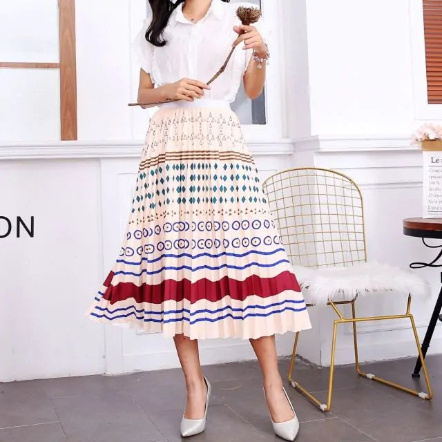 Pleated midi skirt with a gradient design, transitioning from dark black at the waistband to a soft blush pink at the hem, hanging on a black clothing rack next to a vintage-style camera.
