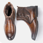 A pair of brown ankle boots with a polished crocodile-embossed finish, side zipper closure, and soft faux-fur lining visible around the collar and inside. The boots combine textured and smooth leather-look panels with sturdy low block soles, giving them a warm, dressy winter style against a plain light background.