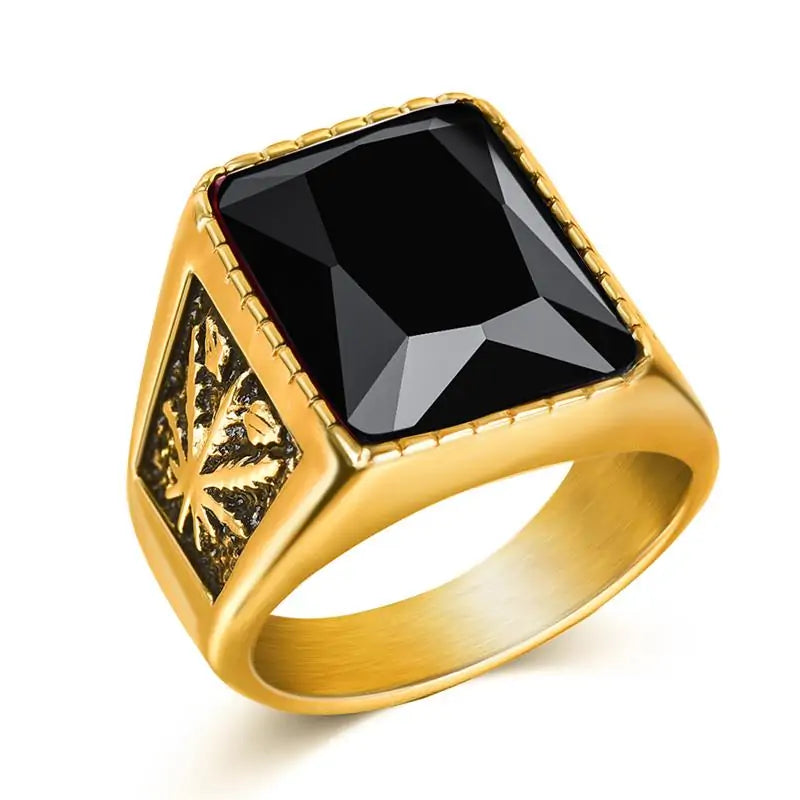 Gold-toned signet-style ring with a large square-cut black gemstone set on top and an engraved side panel, shown on a white background.