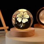 A decorative glass orb with a carved four-leaf clover design inside, illuminated by soft light.