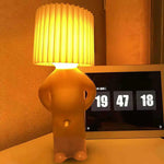 Cute character table lamp with a pleated shade and warm yellow glow.
