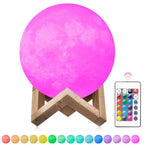 A glowing pink moon-shaped lamp on a wooden stand, shown with a color-changing remote and a row of different color options along the bottom.
