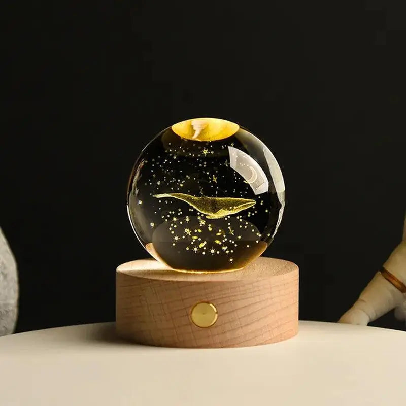 Glass crystal ball night light with a gold “cloud” and starry speckles inside, sitting on a wooden base against a dark background.