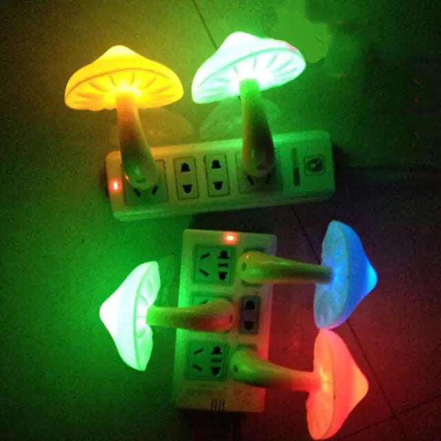 A dimly lit photo of several mushroom-shaped LED night lights plugged into wall power strips, glowing in different colors (yellow, green, blue, and red) and casting colorful light on the surrounding wall.