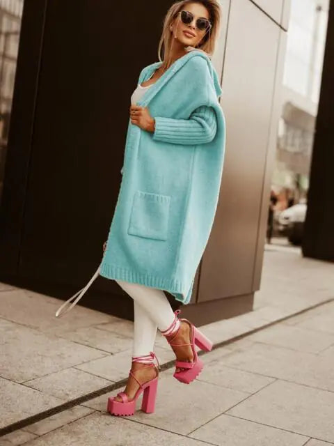 Woman wearing a long light blue cardigan on a city street.