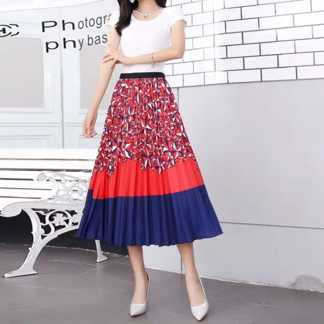 Pleated midi skirt with a gradient design, transitioning from dark black at the waistband to a soft blush pink at the hem, hanging on a black clothing rack next to a vintage-style camera.