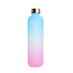 Gradient reusable water bottle fading from blue to pink with a metallic screw-on cap and faint time-marker measurements printed down the front, shown on a white background.