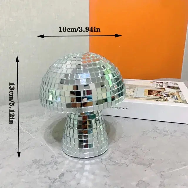 Small disco-ball mosaic mushroom ornament with size measurements (10 cm wide, 13 cm tall) on a tabletop.
