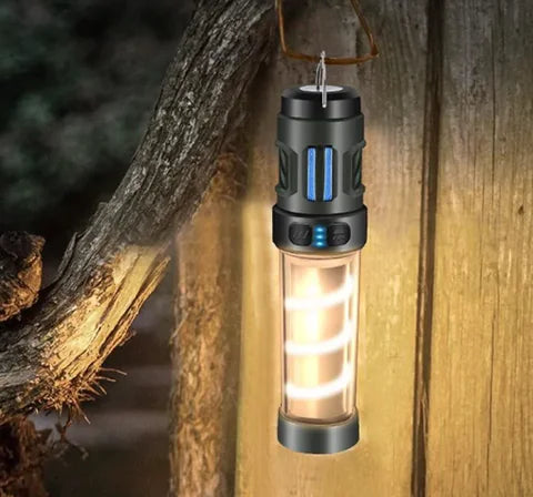 Rechargeable camping lantern with a glowing tube and blue indicator lights hanging from a hook on a wooden post outdoors at night.