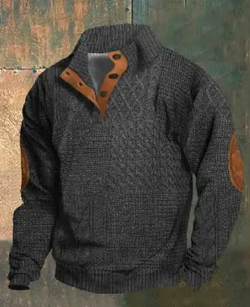 A dark brown men's pullover sweater with a textured cable knit pattern on the front. The sweater features a high ribbed collar with tan brown buttoned detailing, ribbed cuffs and hem, and matching tan elbow patches. The background consists of distressed, multicolored metal panels.