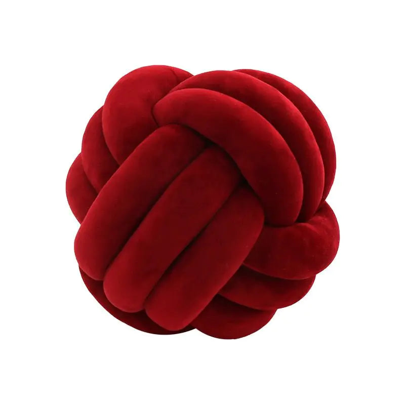 Deep red plush knot pillow made of thick braided tubes, shown against a white background.
