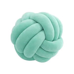 Bright light green plush knot cushion shaped like an interwoven ball, shown on a white background.