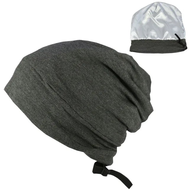 A set of two hats: one is a loose-fitting gray beanie with an adjustable strap, and the other is a small, shiny silver satin bonnet, likely used for protecting hair or as a sleeping cap.