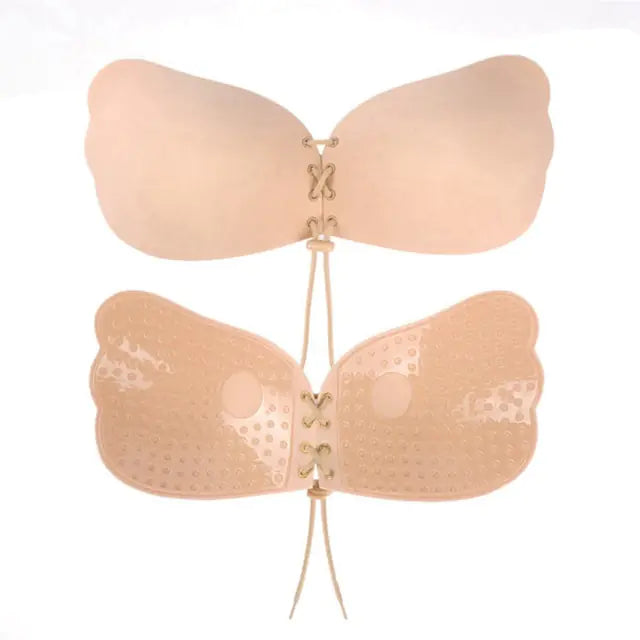 Two beige adhesive strapless bras with lace-up front ties—one smooth and one perforated—shown on a white background.