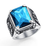 Silver-toned ring with a large square-cut blue gemstone and dark engraved detailing on the band.