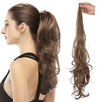 Model with a high ponytail wearing a long, wavy hair extension piece in brown, held up by hand on the right.