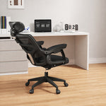 Black office chair in front of a white desk with a laptop and decor items.