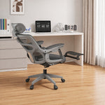 Grey office chair in front of a white desk with a laptop and decor items.