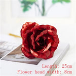 Close-up of a red artificial rose on a tabletop beside a keyboard and book, with overlay text reading “Length: 25cm” and “Flower head width: 8cm.”