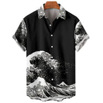 A studio product image of a black short-sleeve button-up shirt on a hanger, featuring a bold white graphic print of stylized ocean waves and spray across the lower half and sleeves, with a matching patterned collar and white buttons, set against a plain light background.