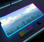 RGB-lit gaming desk mat with a mountain-and-forest landscape design, placed on a dark desk beside a rainbow-backlit mechanical keyboard and a black mouse.