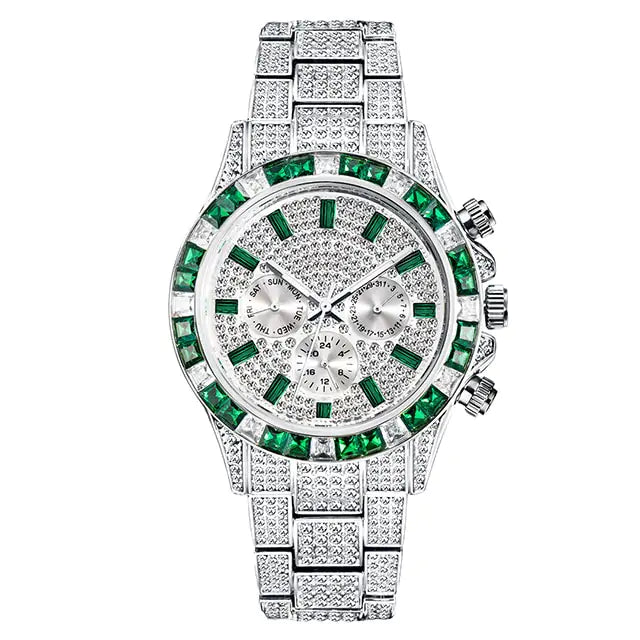Silver-toned luxury wristwatch covered in sparkling stones, with a green gemstone bezel and green hour markers, plus three subdials on the face and a matching metal link bracelet.
