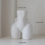 A white ceramic vase shaped like a stylized female torso with small side handles, shown with measurement labels (about 22 cm tall and 17 cm wide) on a neutral background.