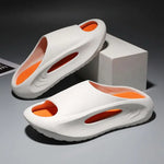 A pair of stylish black slip-on sandals with purple cushioned insoles, featuring cutout designs on the sides and toes, displayed on a white surface next to stacked books.
