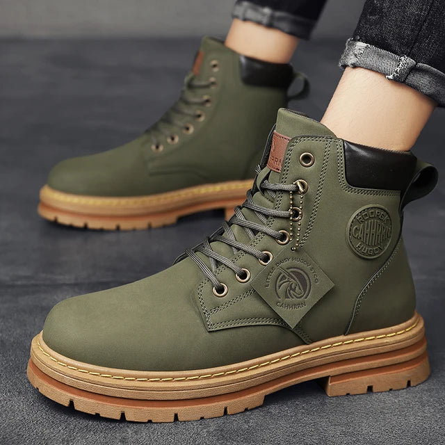 A pair of sleek black leather ankle boots with rugged rubber soles, lace-up fronts, and metal eyelets, displayed on a gray fabric surface with one boot propped up on a vintage-style book for presentation.