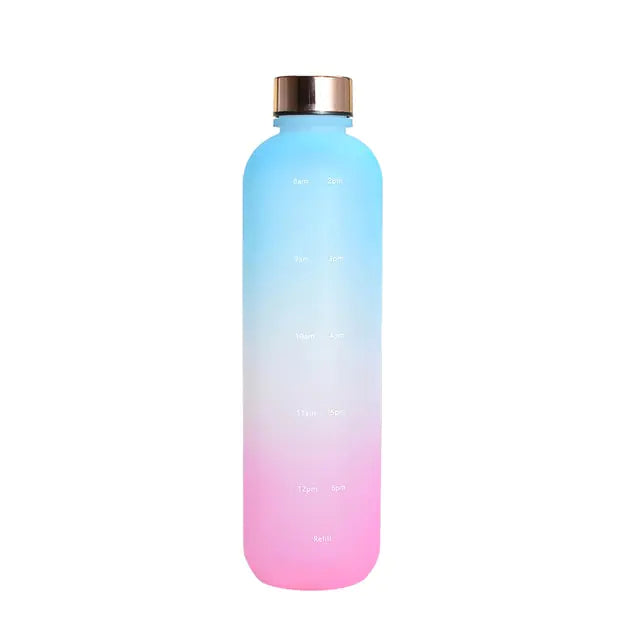 Tall gradient “motivational” water bottle fading from blue to pink with a metallic screw cap, showing faint time markers and reminder text on the front against a white background.