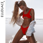 Model on a beach wearing a bright red two-piece bikini with small cutouts under the bust and on the bottoms, posing with a white jacket draped off her shoulders and “ELLOLACE” text along the side.