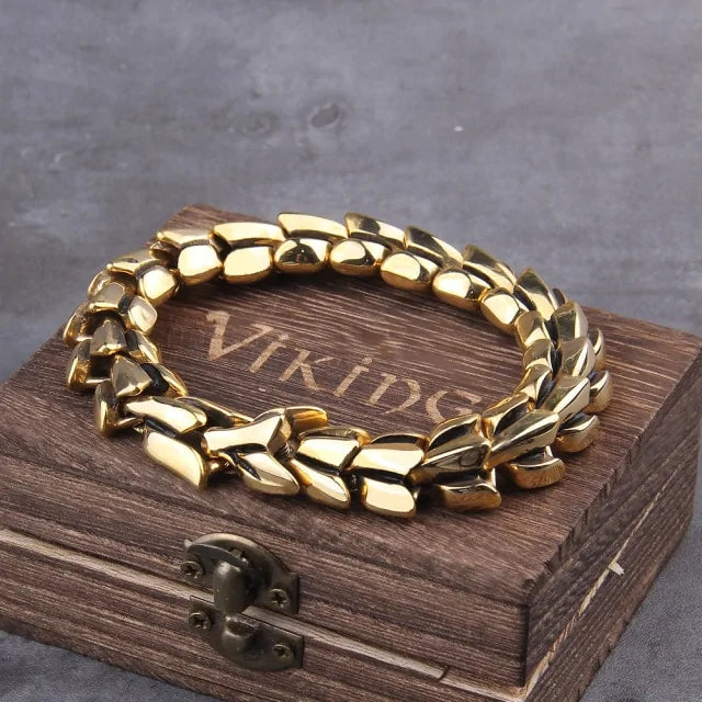 Chunky gold-tone chain bracelet resting on a rustic wooden box engraved “VIKING,” photographed on a gray surface with the box latch visible in front.