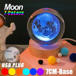 Crystal ball night light with a 3D moon design glowing blue on a wooden base, advertised as ‘Moon 7 Colors’ with USB plug-in and 7 cm base, shown with a cord and small pom-pom balls.
