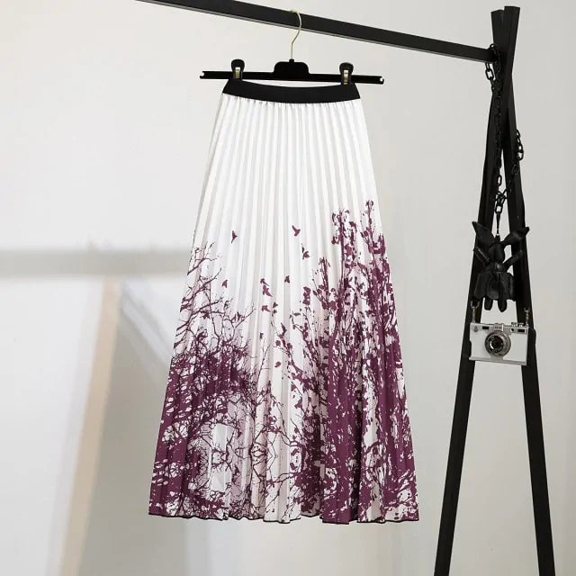Pleated midi skirt with a gradient design, transitioning from dark black at the waistband to a soft blush pink at the hem, hanging on a black clothing rack next to a vintage-style camera.