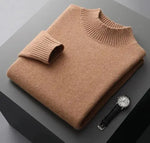 A neatly folded beige knitted sweater with a ribbed high collar and cuffs, placed on a dark grey surface. Beside the sweater, a classic wristwatch with a black leather strap and a silver dial is positioned, adding a touch of elegance to the composition.