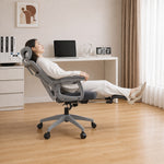 Person relaxing on a gray office chair in a home office setting.