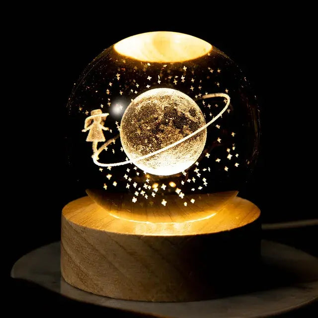 A glowing globe featuring a girl floating around a planet with a ring, surrounded by stars, sitting on a wooden base.