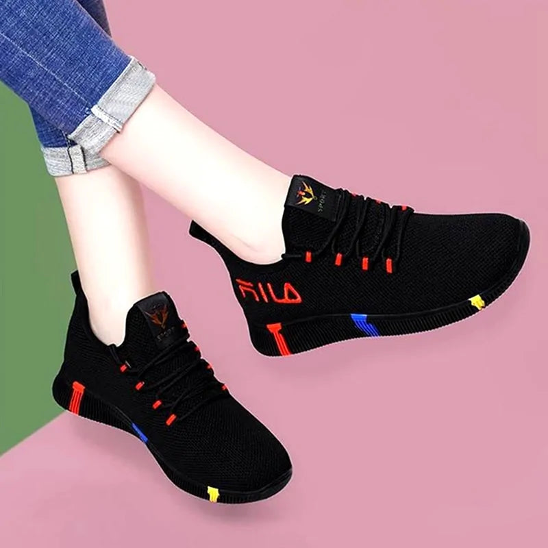 A pair of stylish mesh sneakers worn with jeans. The shoes feature colorful embroidered details The sneakers have a sleek, breathable design and a casual, trendy aesthetic.