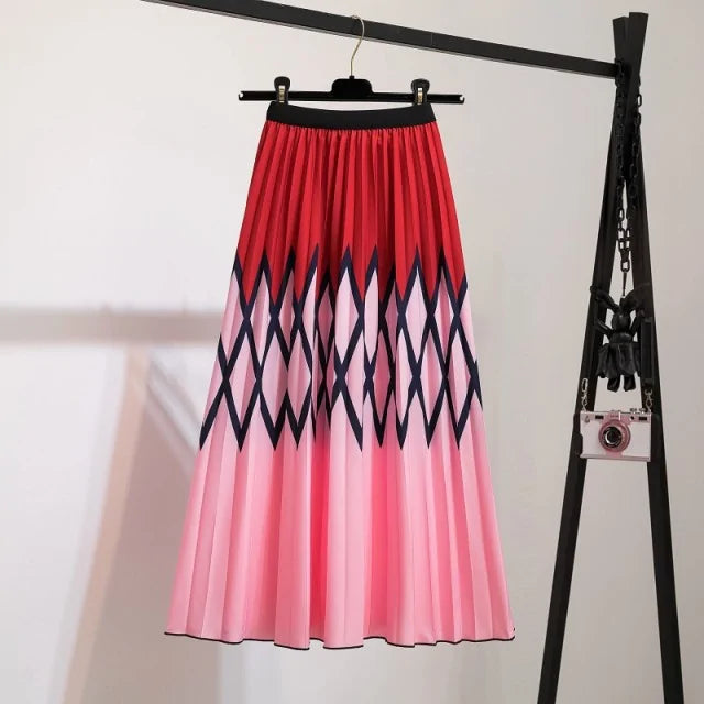 Pleated midi skirt with a gradient design, transitioning from dark black at the waistband to a soft blush pink at the hem, hanging on a black clothing rack next to a vintage-style camera.