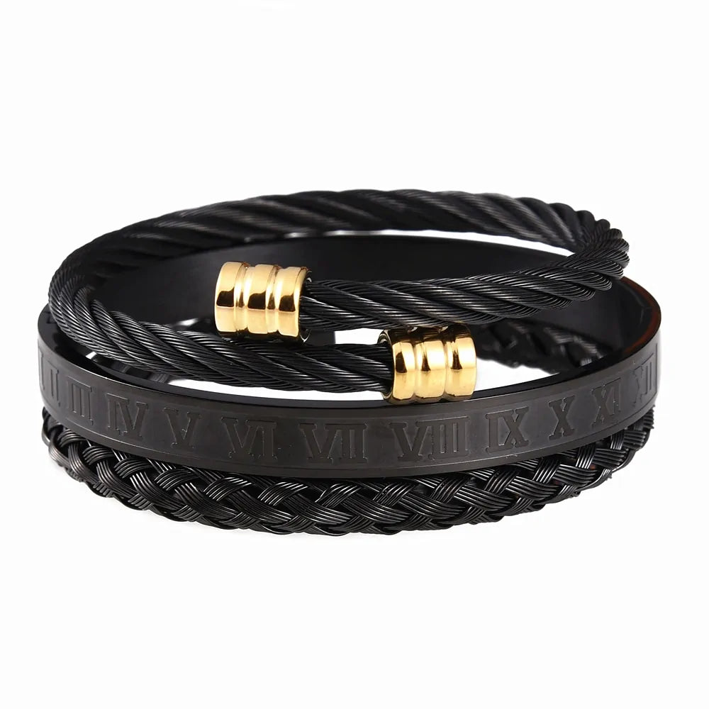 A layered black men’s bracelet set on a white background, featuring twisted cable-style bands with small gold-tone metal rings and a wide black band engraved with Roman numerals.