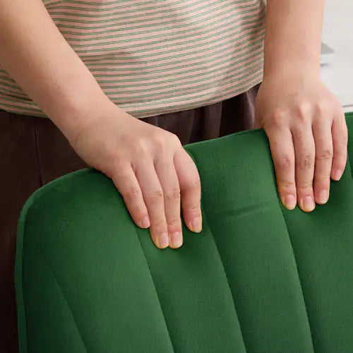 Person holding a green cushion with a striped shirt and brown pants.