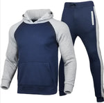 A stylish two-piece men's tracksuit. The set includes a hooded sweatshirt with a kangaroo pocket and long gray sleeves, along with matching jogger pants that have a drawstring waist and gray side panels with zippered pockets. The design offers a sporty yet casual look, ideal for workouts or everyday wear.