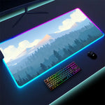 Large gaming mouse pad with a mountain-and-forest landscape design and glowing RGB light strip around the edges, shown on a desk with a rainbow-backlit keyboard and a mouse.