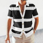 Man wearing a short-sleeve button-up knit shirt with wide black-and-white horizontal stripes, a white collar and placket, and large buttons, paired with light-colored pants.