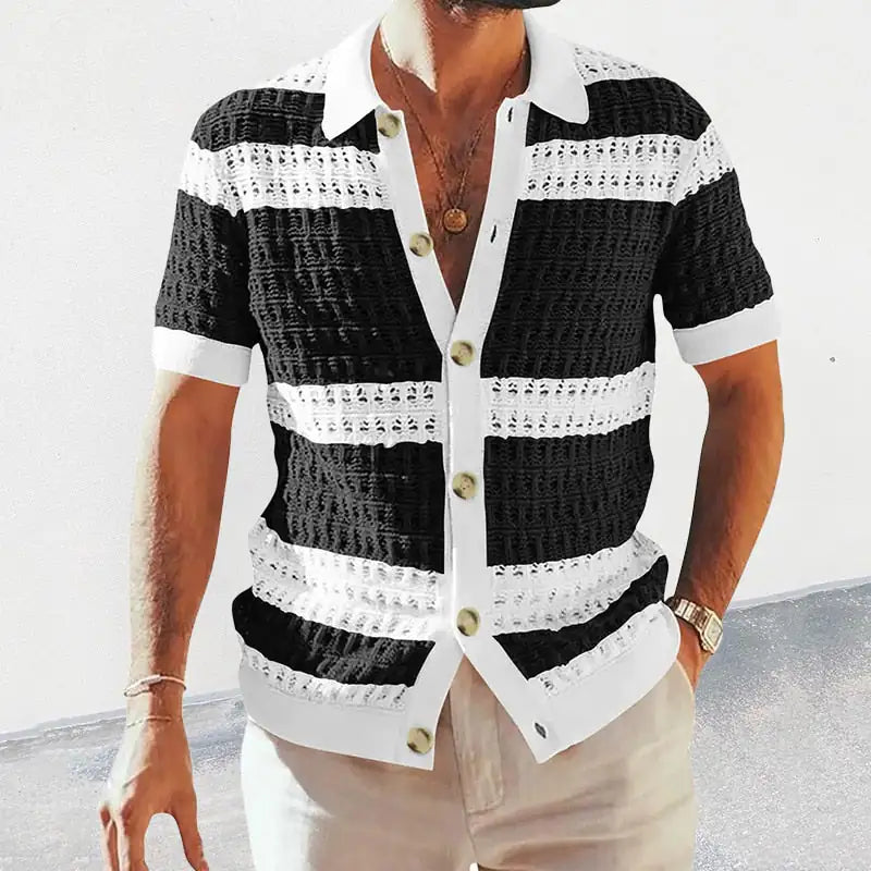Man wearing a short-sleeve button-up knit shirt with wide black-and-white horizontal stripes, a white collar and placket, and large buttons, paired with light-colored pants.