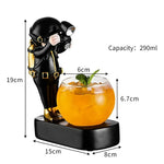 Black diver figurine cocktail glass holder with a round 290ml glass, decorative base and gold accent details.

