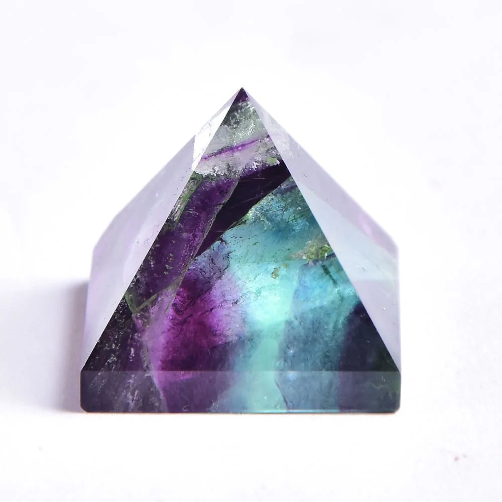 A small, polished crystal pyramid with translucent layers of deep purple and teal-green inside, photographed against a white background.