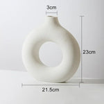 Matte off-white donut-shaped ceramic vase with a small neck, shown against a light background with dimensions labeled: 23 cm tall, 21.5 cm wide, and a 3 cm opening at the top.