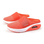 Coral slip-on mesh mule sneakers with wide elastic strap, open back, thick white platform sole, and visible air-cushion heel detail.